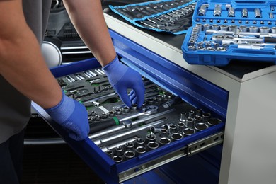 Auto mechanic with different tools at automobile repair shop, closeup