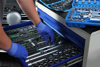 Auto mechanic with different tools at automobile repair shop, closeup