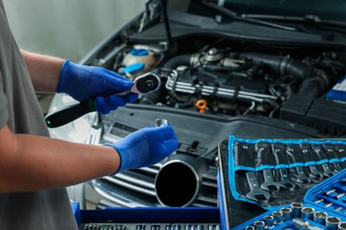 Auto mechanic with different tools at automobile repair shop, closeup