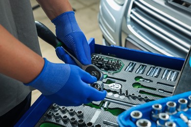 Photo of Auto mechanic with different tools at automobile repair shop, closeup