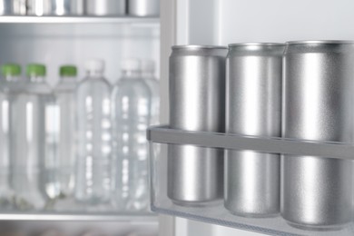 Cans of beer and water bottles in refrigerator, closeup