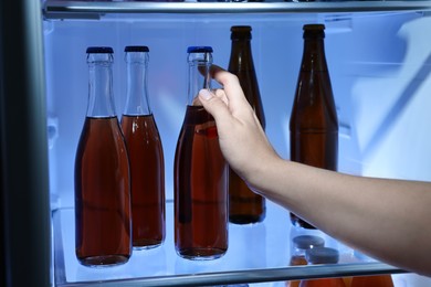 Woman taking bottle with drink from refrigerator, closeup