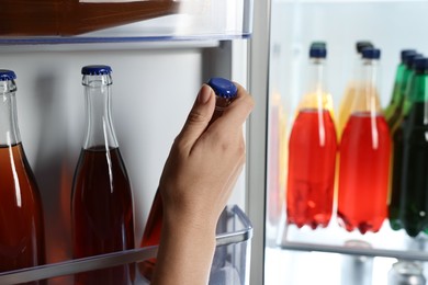 Photo of Woman taking bottle with drink from refrigerator, closeup