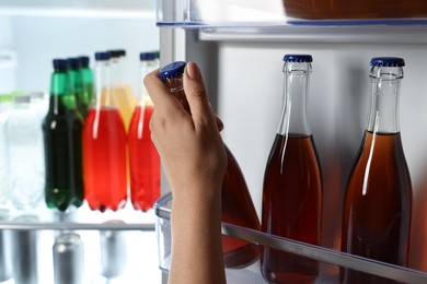 Woman taking bottle with drink from refrigerator, closeup