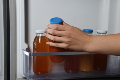 Woman taking bottle of juice from refrigerator, closeup