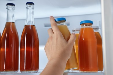 Woman taking bottle with drink from refrigerator, closeup