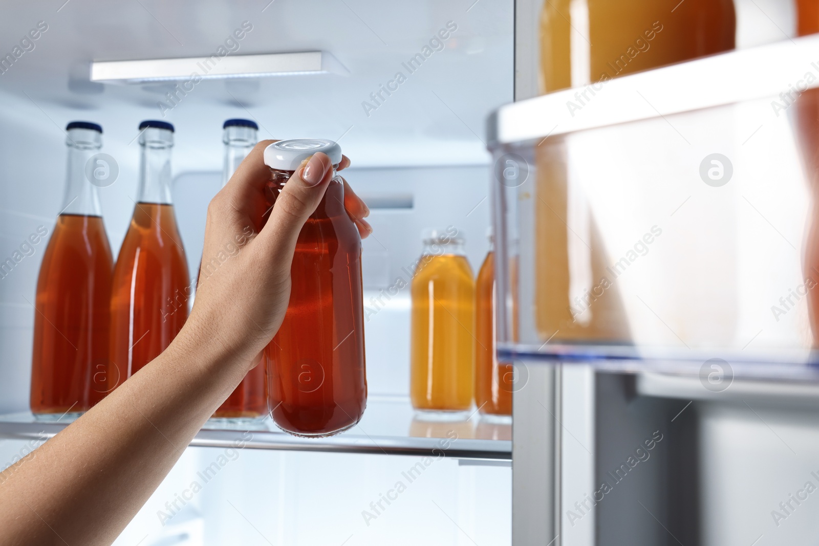 Photo of Woman taking bottle with drink from refrigerator, closeup