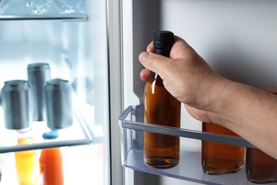 Woman taking bottle with drink from refrigerator, closeup