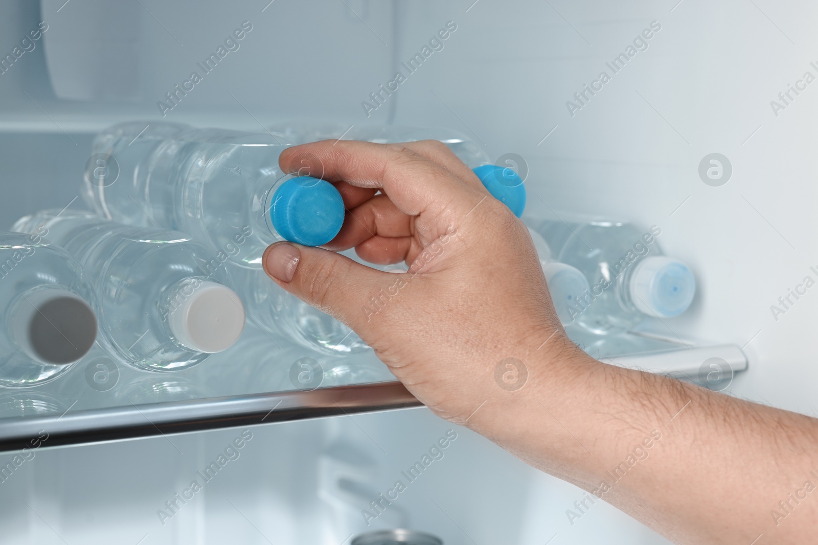 Photo of Woman taking bottle of water from refrigerator, closeup