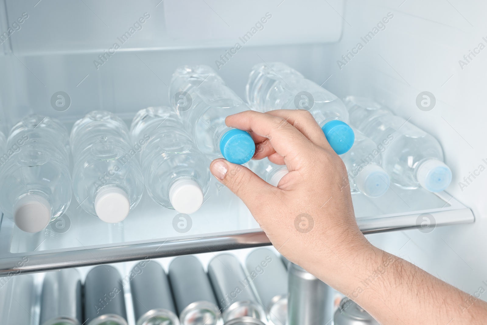 Photo of Woman taking bottle of water from refrigerator, closeup