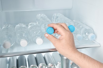 Woman taking bottle of water from refrigerator, closeup