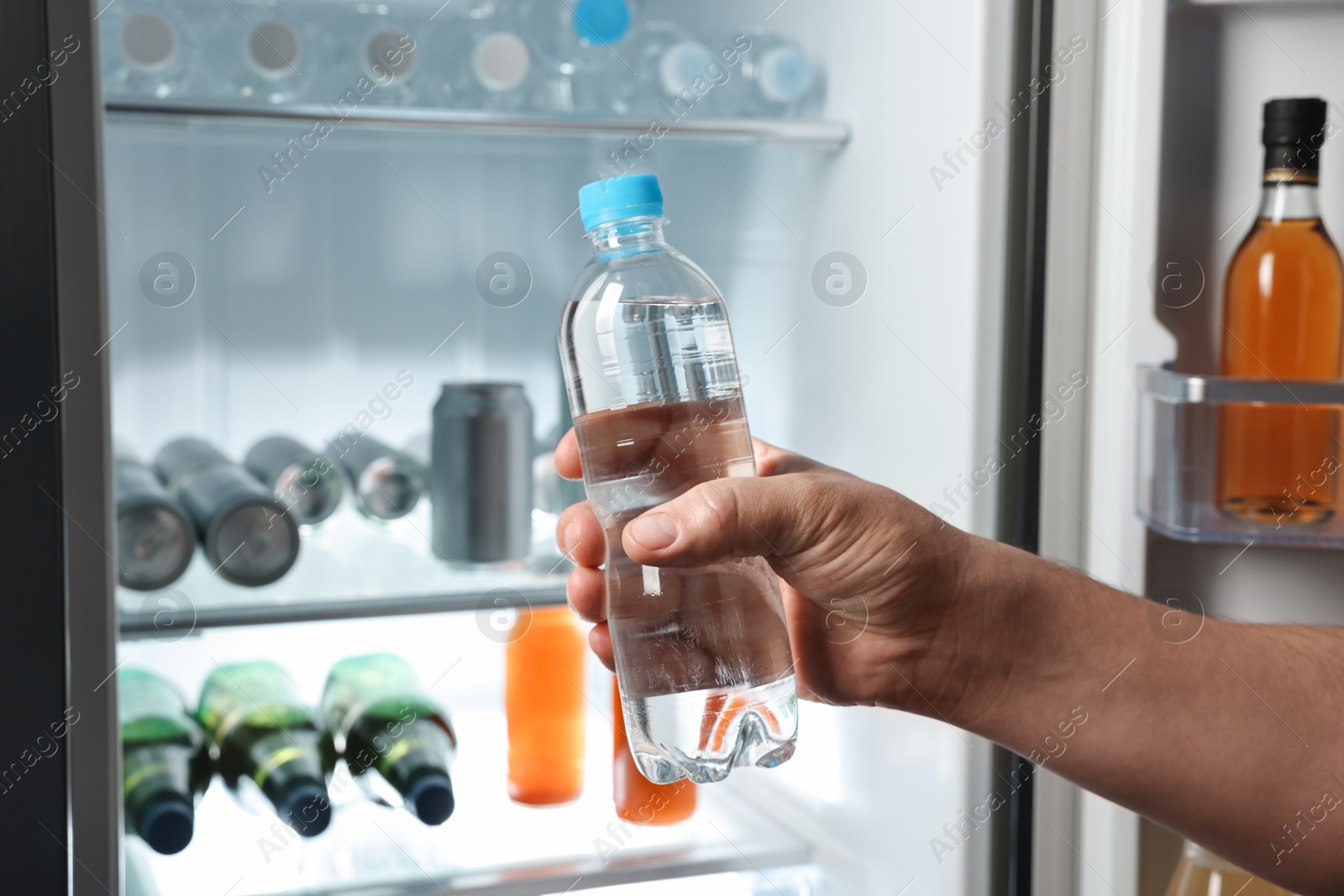 Photo of Woman taking bottle of water from refrigerator, closeup