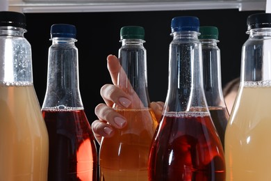 Photo of Woman taking bottle of soda drink from refrigerator, closeup