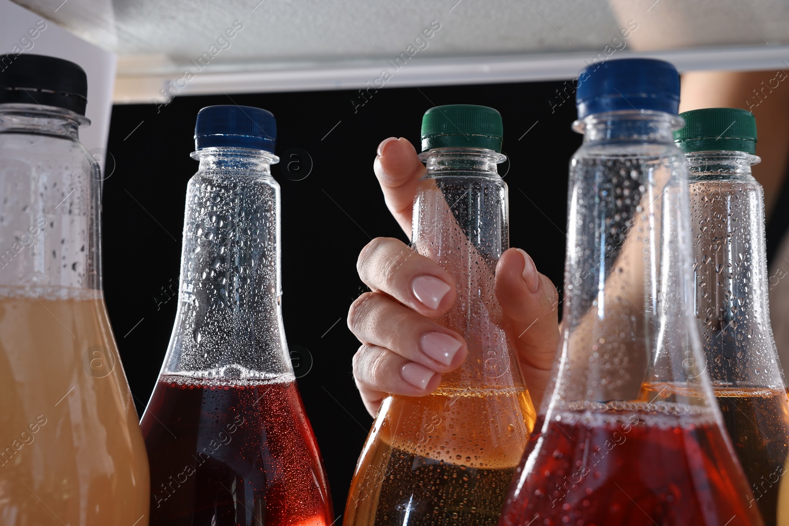 Photo of Woman taking bottle of soda drink from refrigerator, closeup