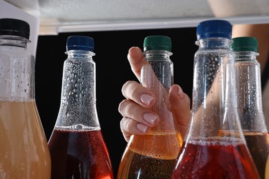 Photo of Woman taking bottle of soda drink from refrigerator, closeup