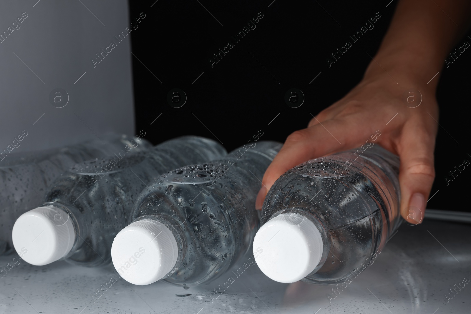 Photo of Woman taking bottle of water from refrigerator, closeup