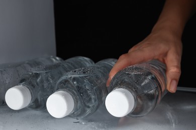 Woman taking bottle of water from refrigerator, closeup