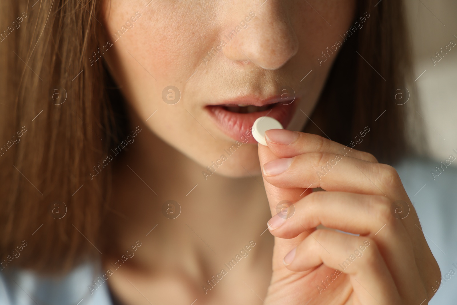 Photo of Woman taking pill on blurred background, closeup