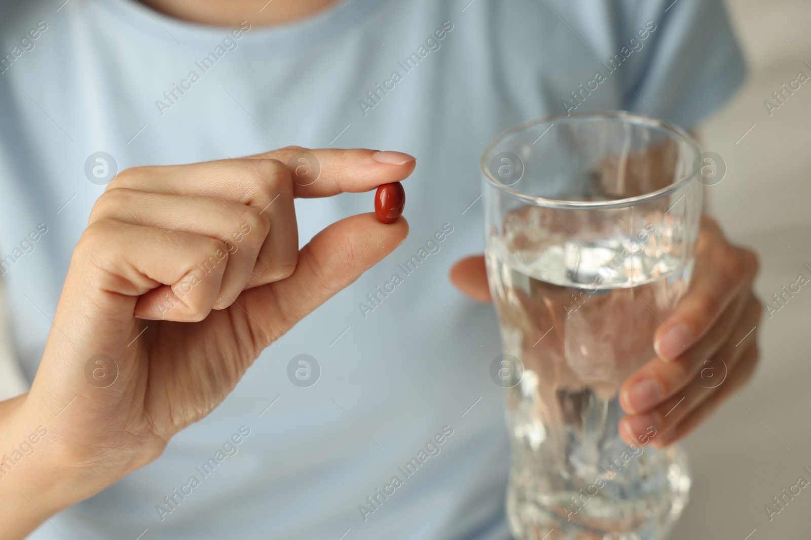 Photo of Woman with glass of water and pill indoors, closeup