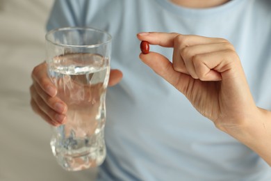 Photo of Woman with glass of water and pill indoors, closeup