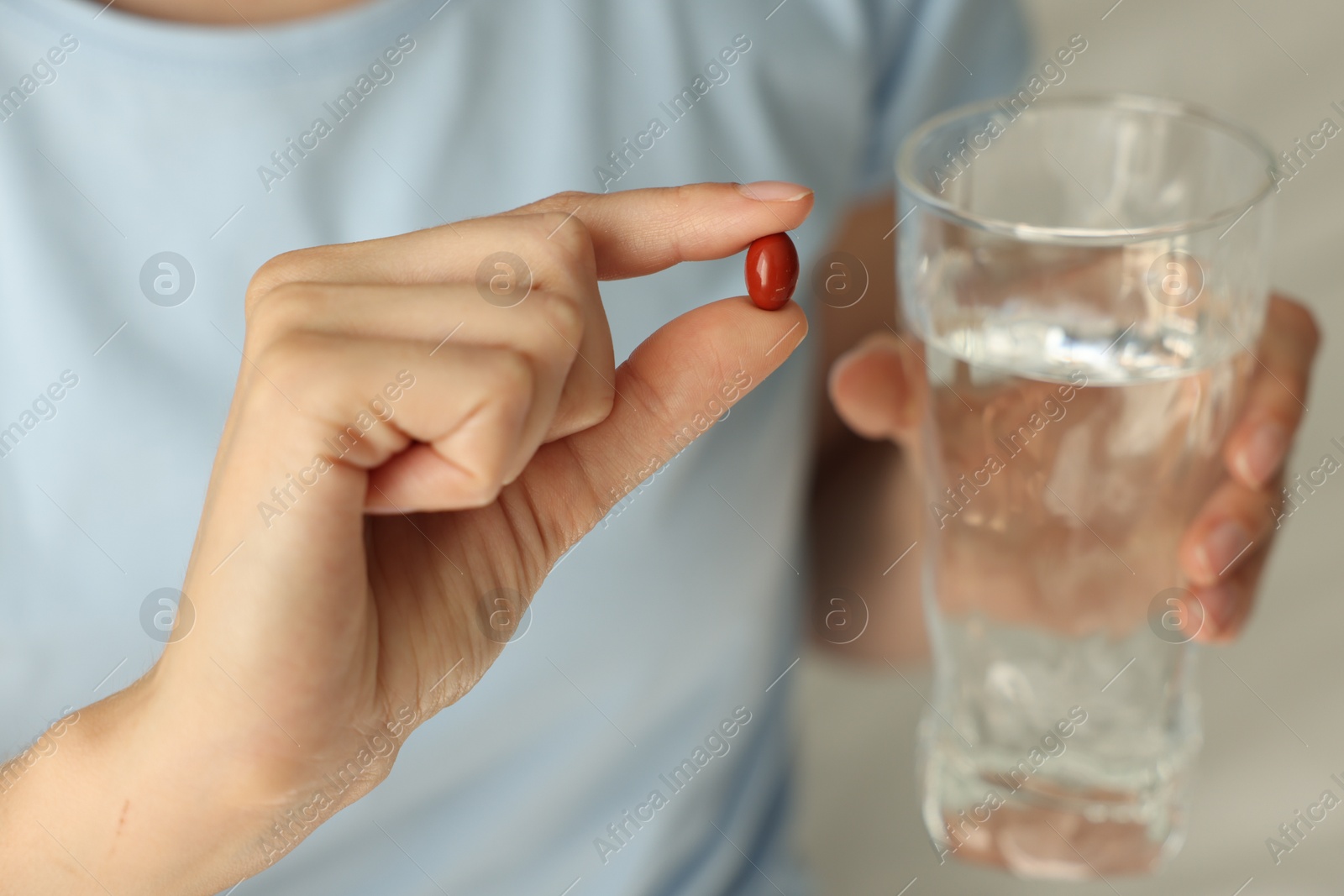 Photo of Woman with glass of water and pill indoors, closeup