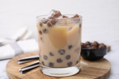 Photo of Tasty milk bubble tea in glass, tapioca pearls and straws on table, closeup