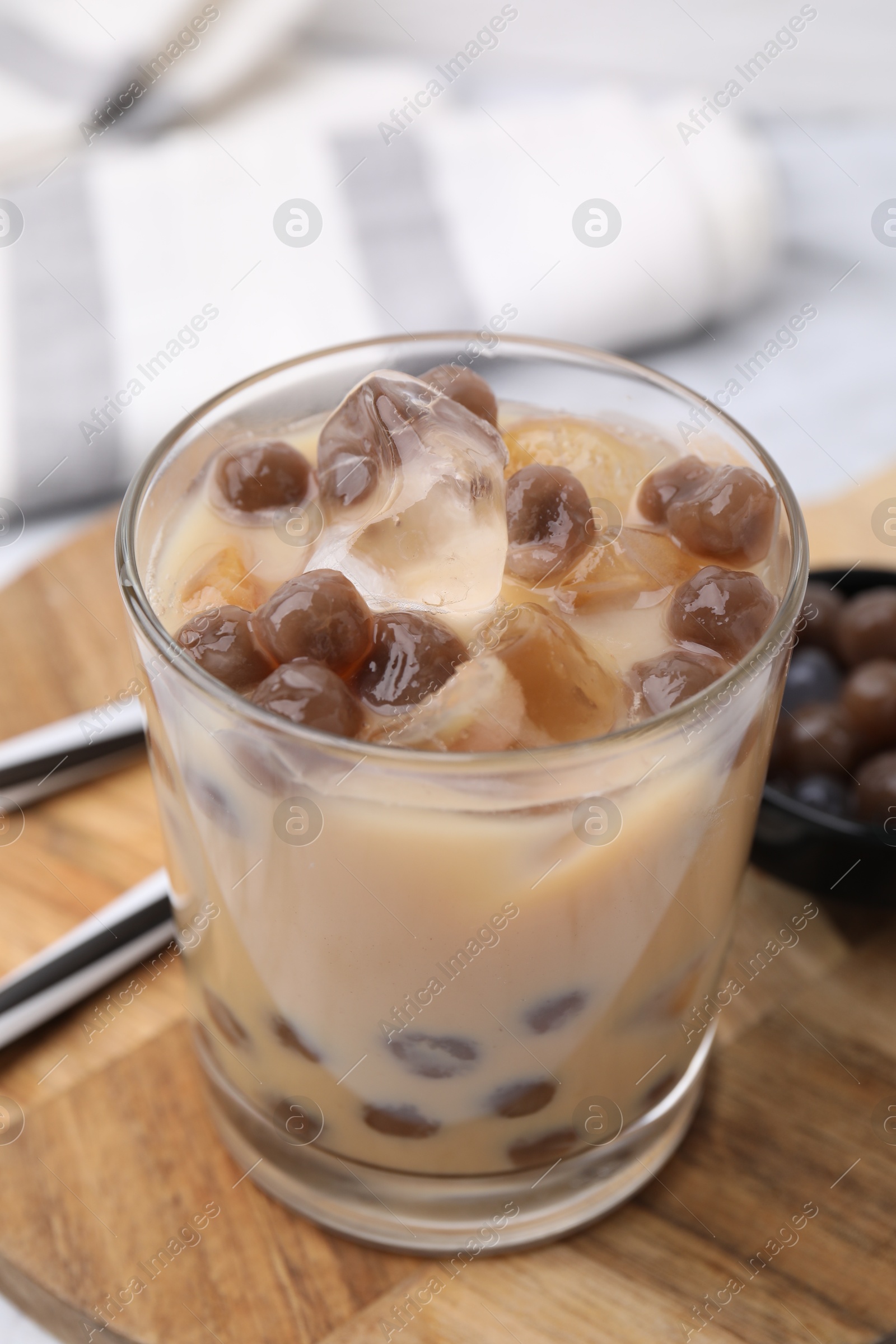 Photo of Tasty milk bubble tea in glass, tapioca pearls and straws on table, closeup