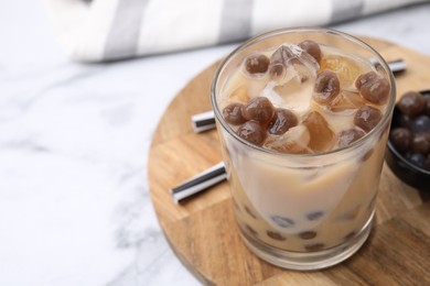 Photo of Tasty milk bubble tea in glass, tapioca pearls and straws on white marble table, closeup. Space for text