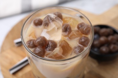 Photo of Tasty milk bubble tea in glass on table, closeup