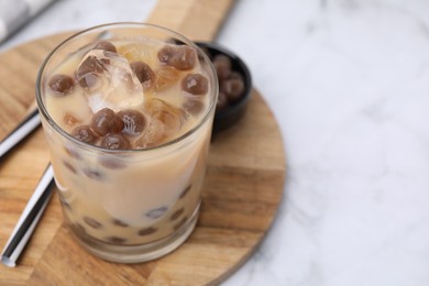 Photo of Tasty milk bubble tea in glass, tapioca pearls and straws on white marble table, closeup. Space for text