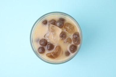 Tasty milk bubble tea in glass on light blue background, top view