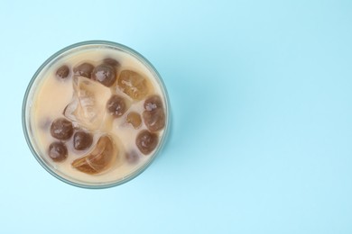 Photo of Tasty milk bubble tea in glass on light blue background, top view. Space for text