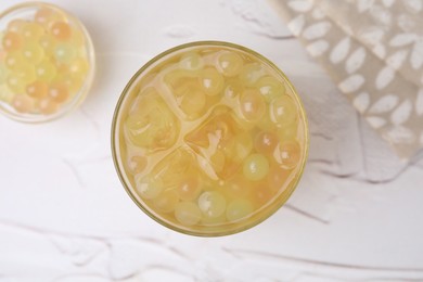 Tasty bubble tea in glass and tapioca pearls on white table, top view