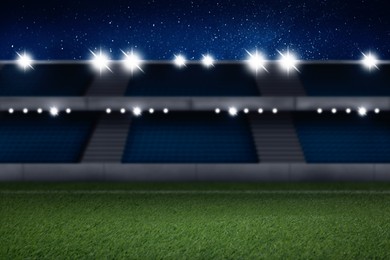 Image of Football stadium with seats, illumination and green grass