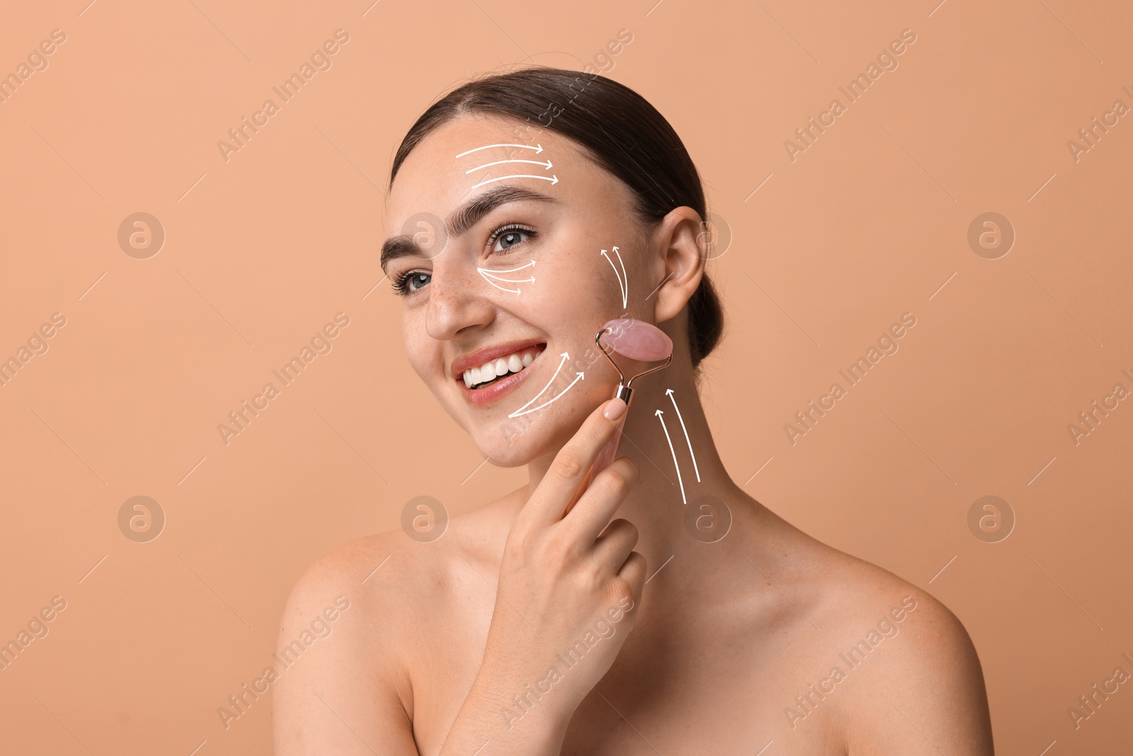 Image of Beautiful young woman doing facial massage with roller on dark beige background. Lines on skin showing directions of motion