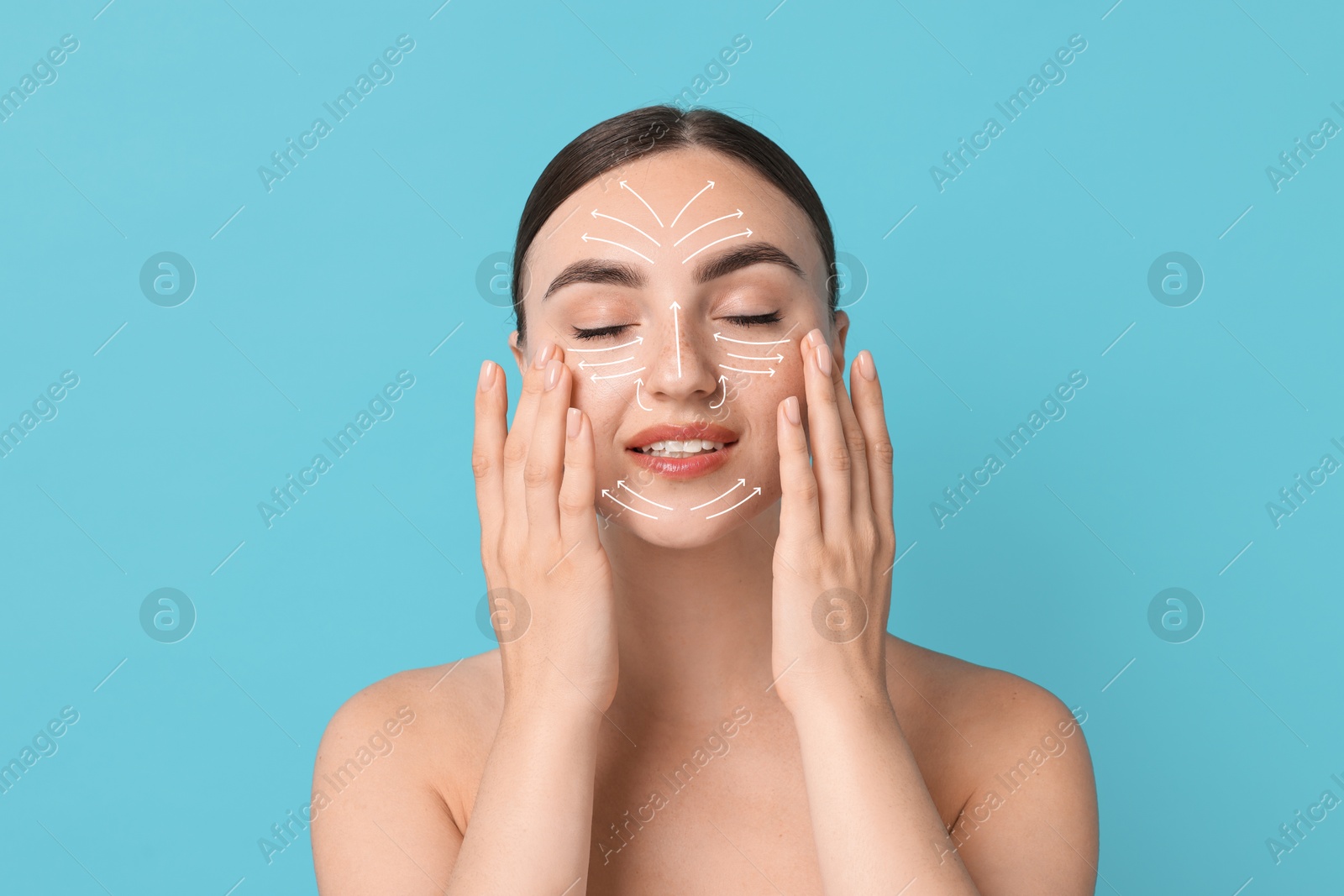 Image of Beautiful young woman doing face massage with fingers on light blue background. Lines on skin showing directions of motion