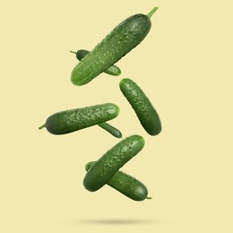 Image of Whole ripe cucumbers falling on dark beige background