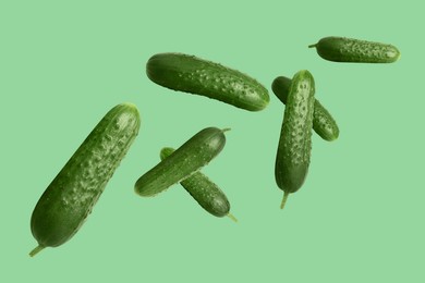 Image of Whole ripe cucumbers flying on green light background