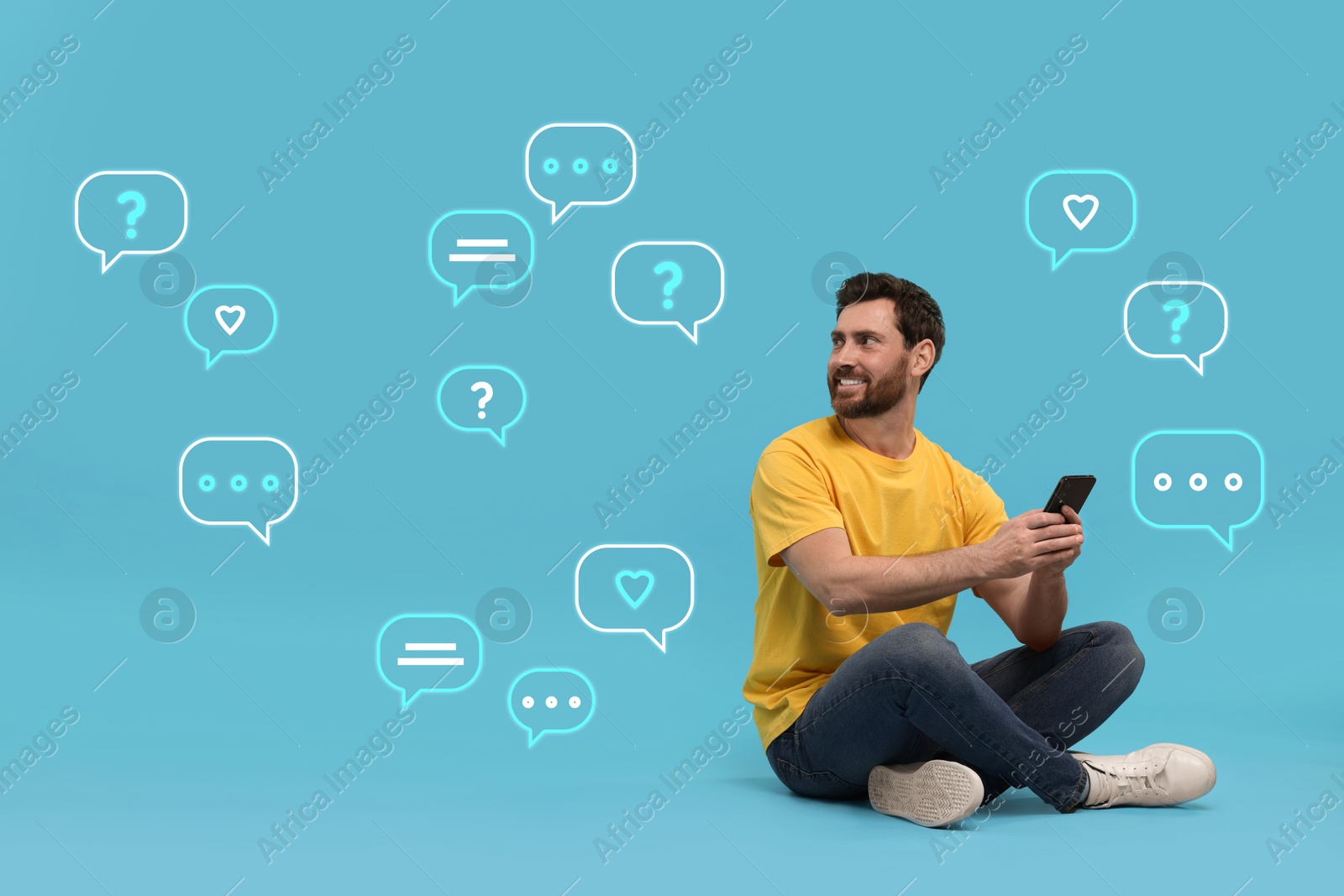 Image of Happy man sending message via smartphone on light blue background. Speech bubbles near him