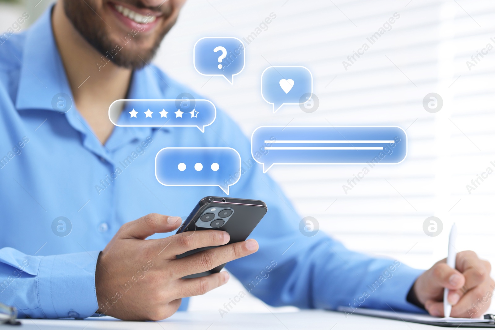 Image of Happy businessman reading message via smartphone at table, closeup. Speech bubbles near device.