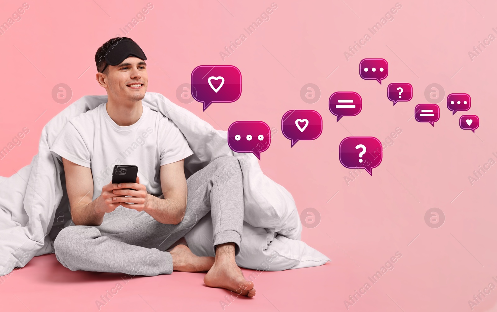 Image of Happy man sending message via smartphone on pink background. Speech bubbles near him