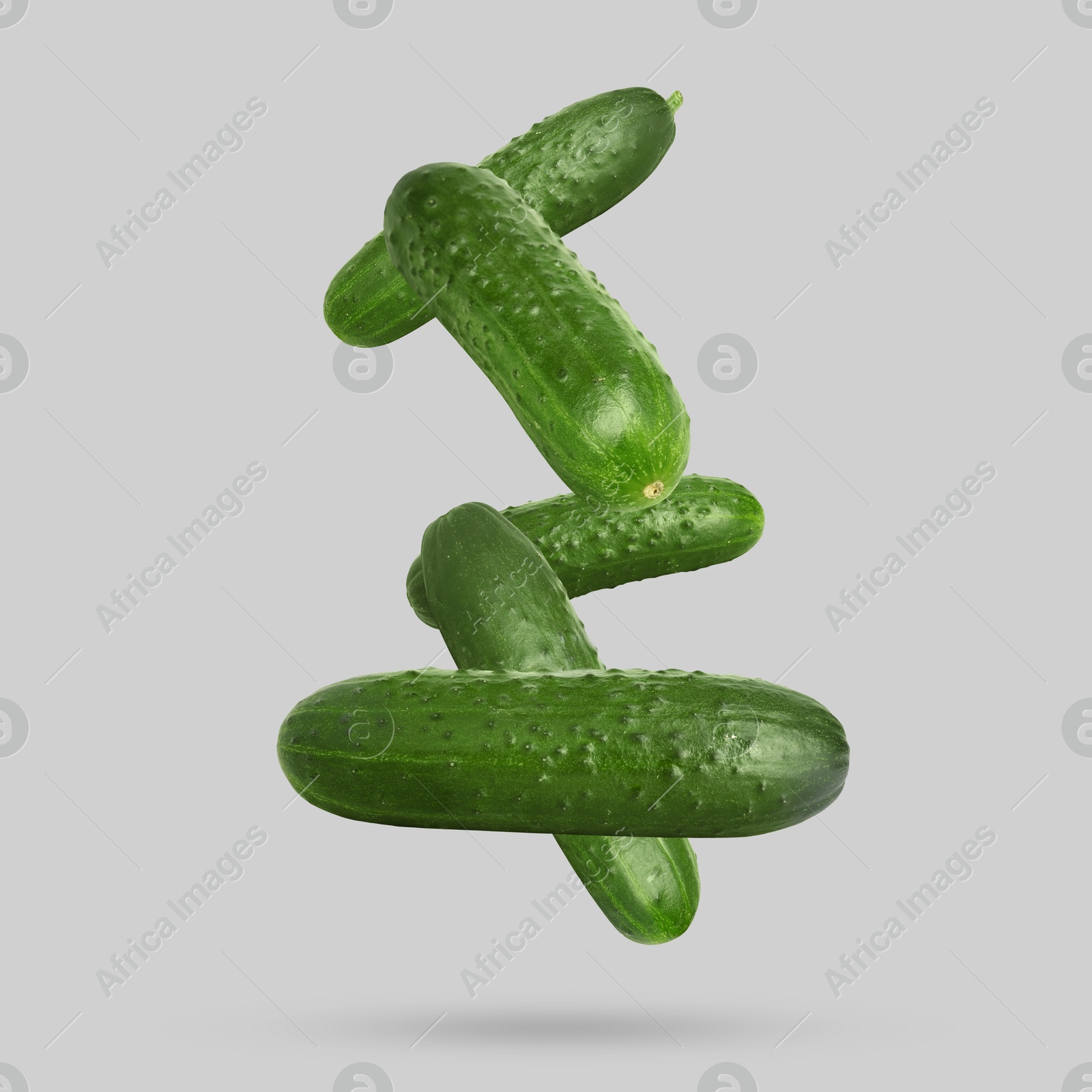 Image of Whole ripe cucumbers falling on grey background