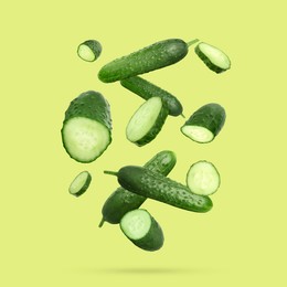 Image of Many ripe cucumbers falling on yellowish green background