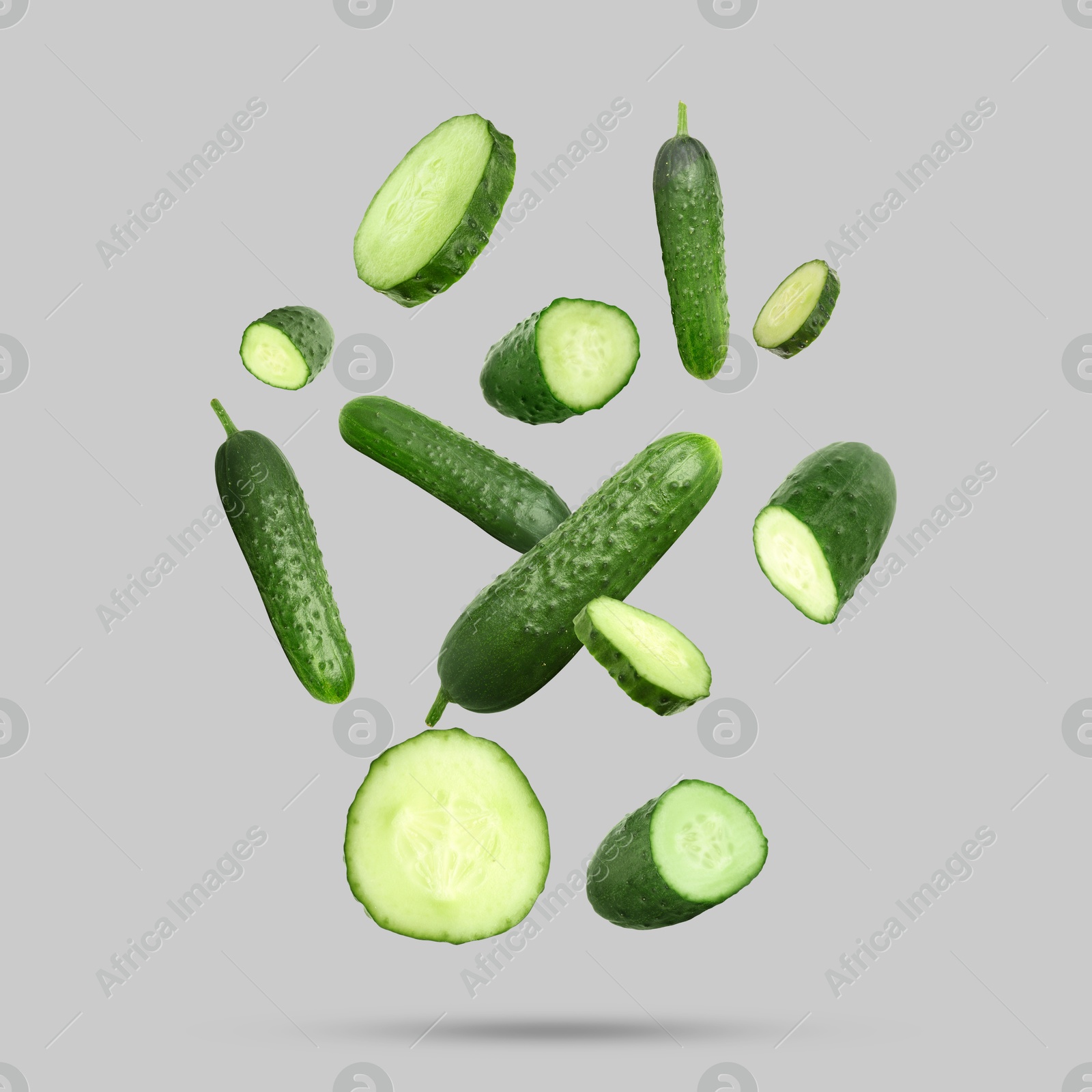 Image of Many ripe cucumbers falling on grey background