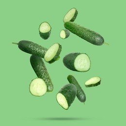 Image of Many ripe cucumbers falling on green background