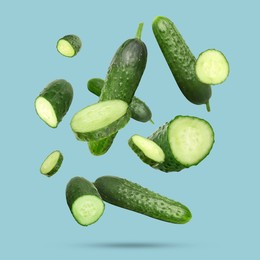 Image of Many ripe cucumbers falling on light blue background