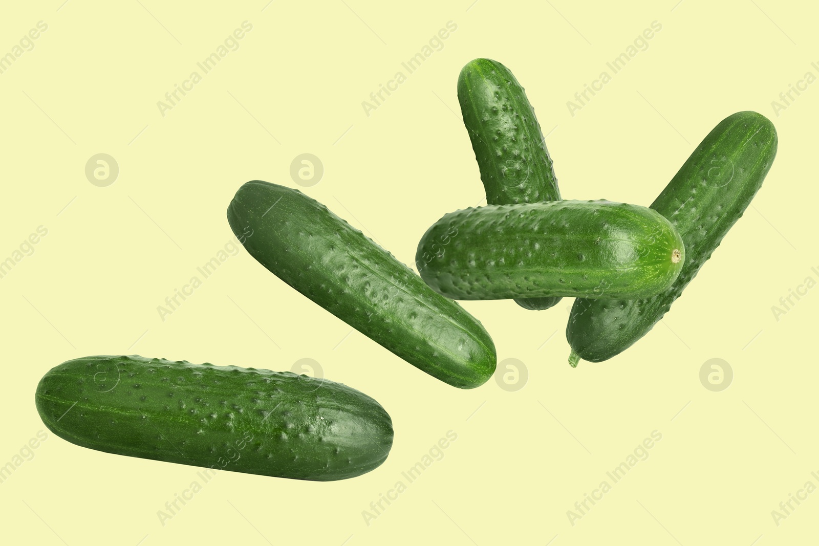 Image of Whole ripe cucumbers flying on beige background