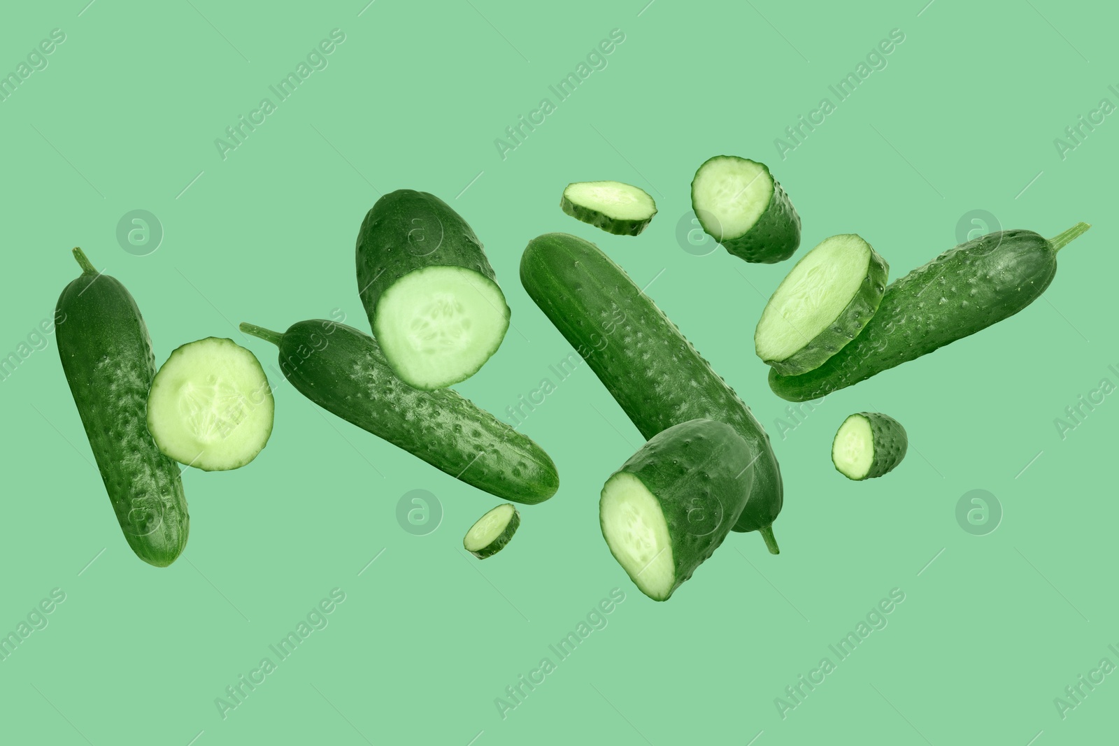 Image of Many ripe cucumbers flying on green background