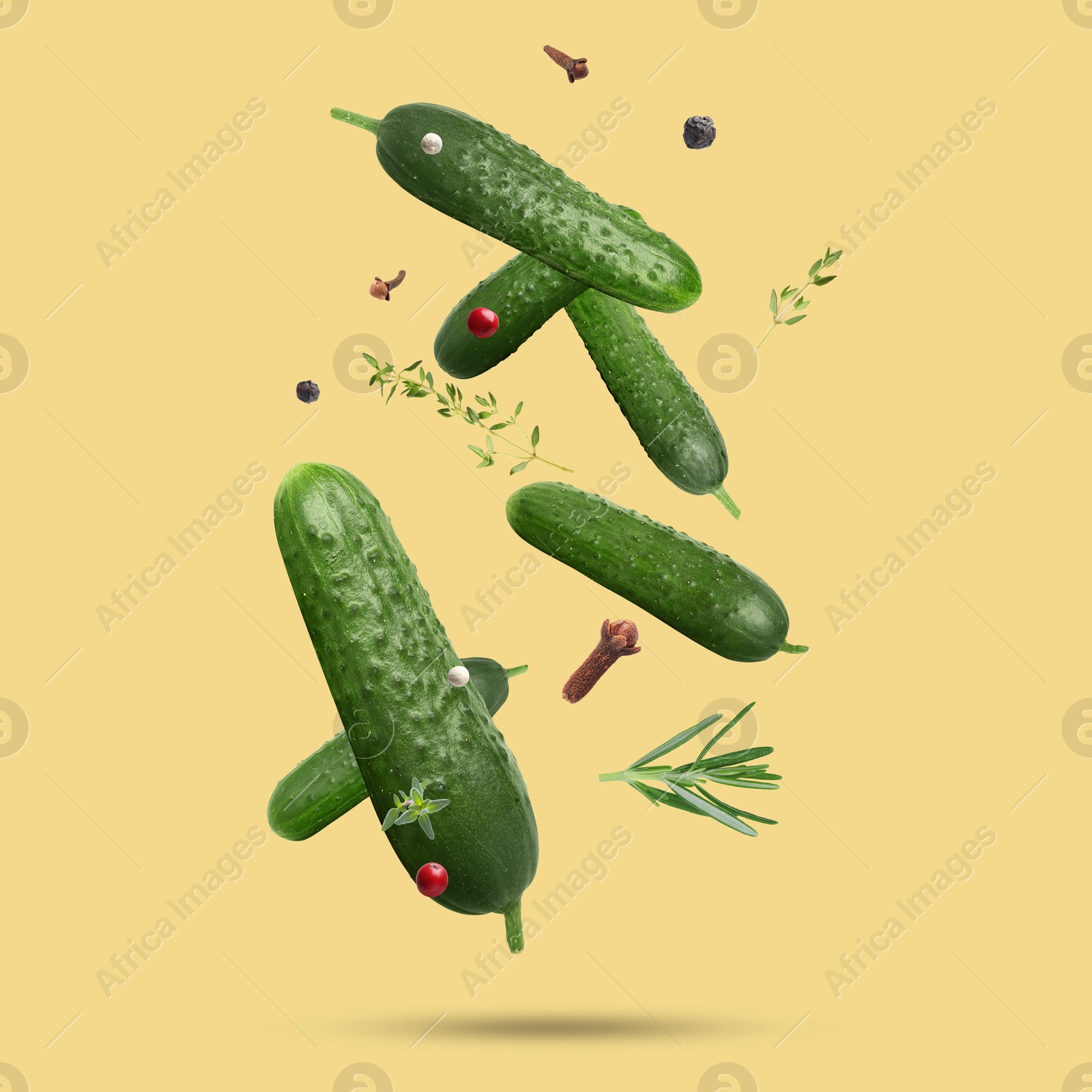 Image of Ripe cucumbers, herbs and spices falling on pale orange background