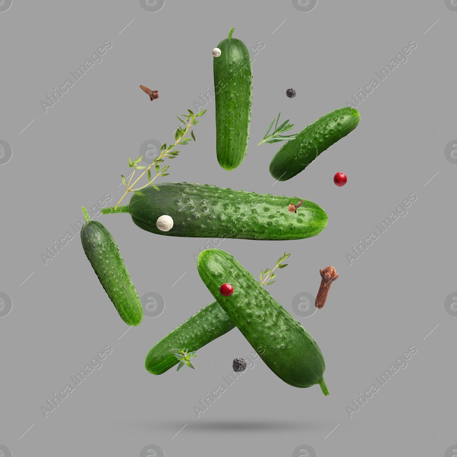 Image of Ripe cucumbers, herbs and spices falling on grey background